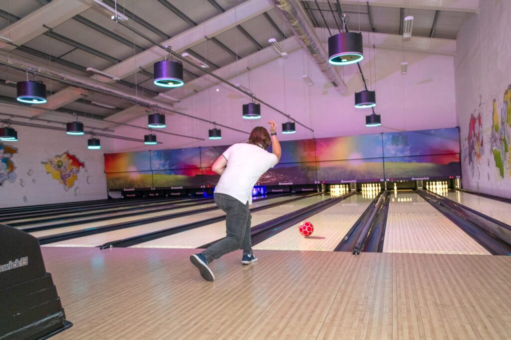 A man throwing a bowling ball down the alley towards the pins