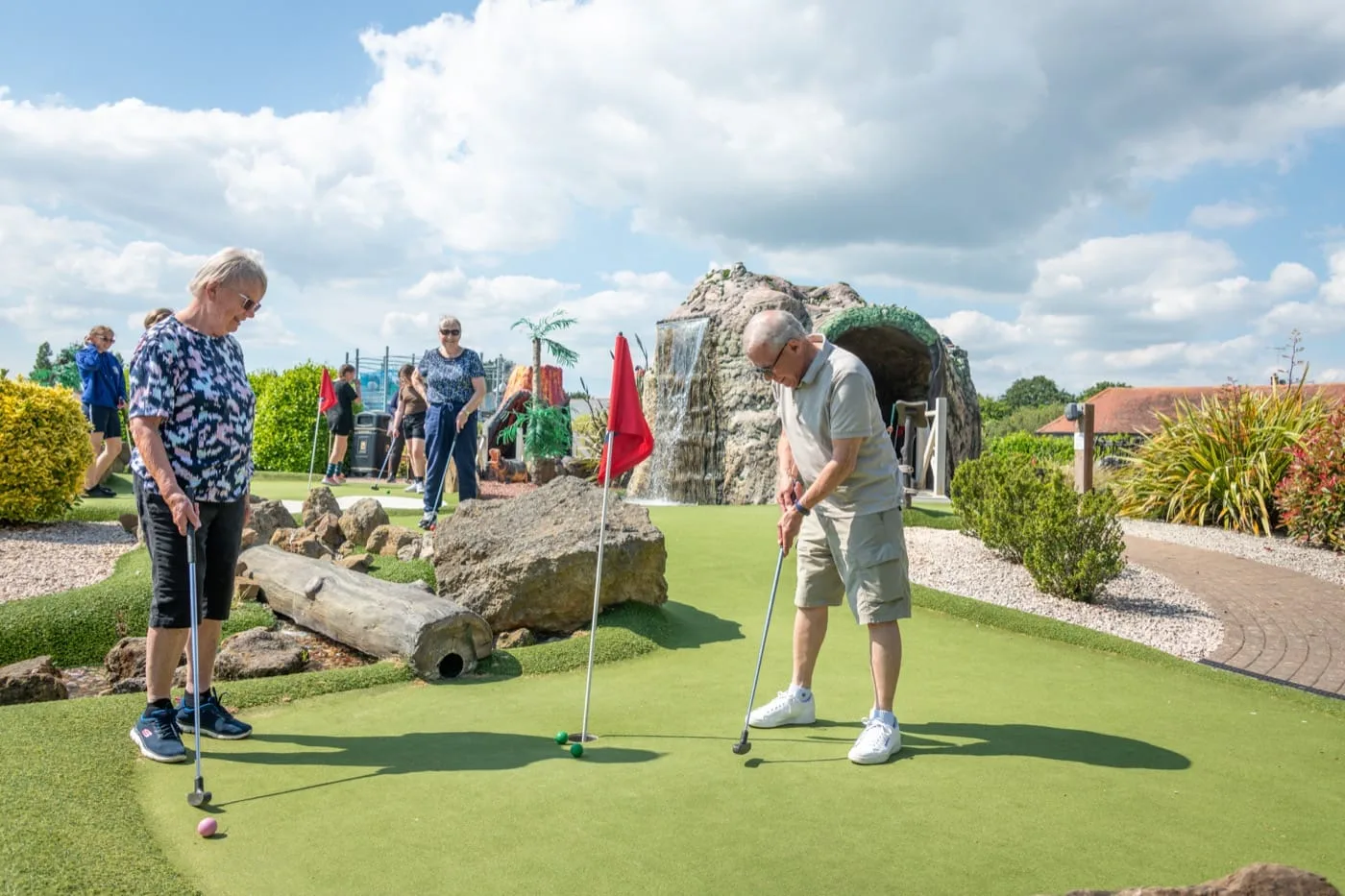 A woman watches as her friend takes a shot on the Adventure Golf